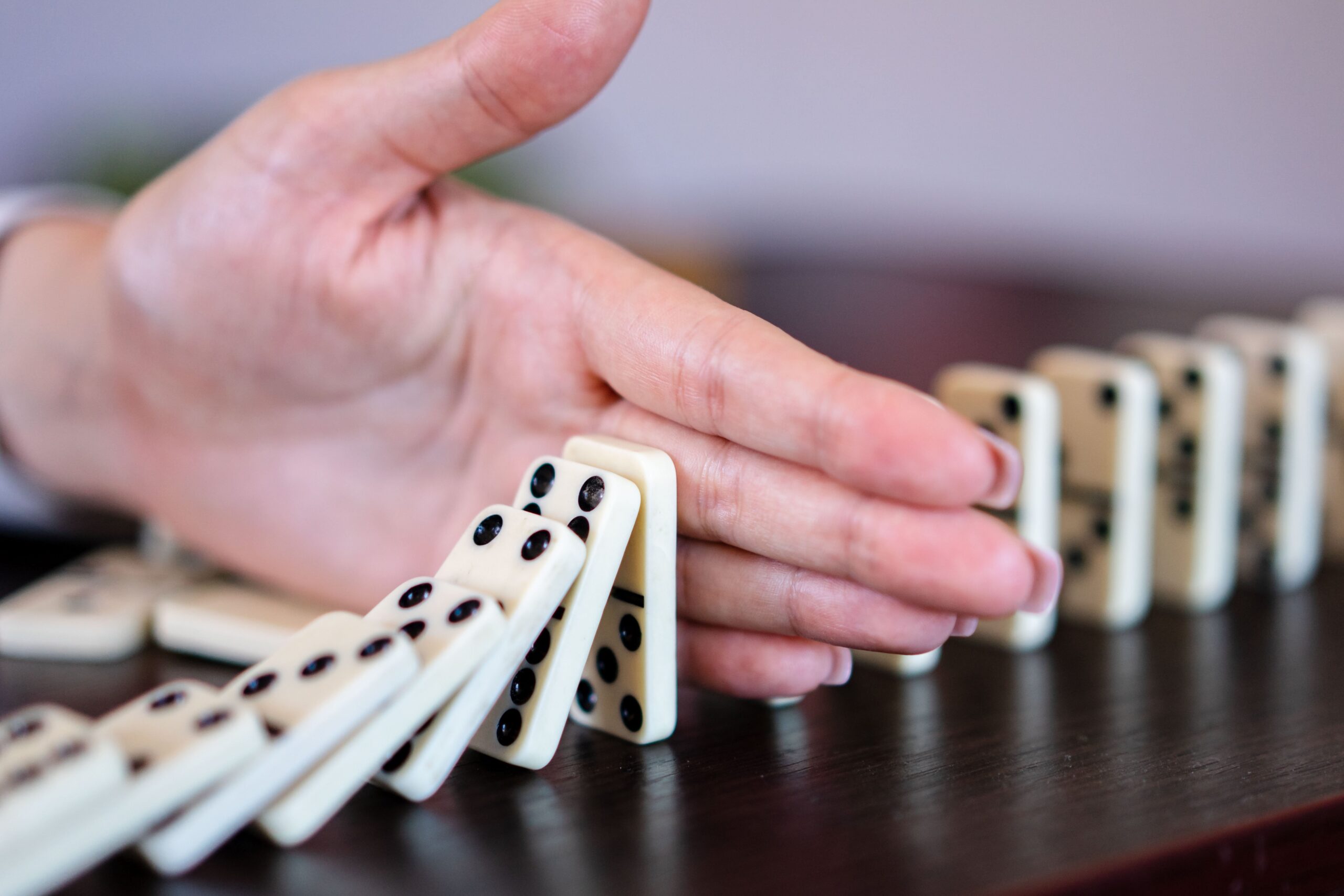 dłoń hamująca lawinę domino